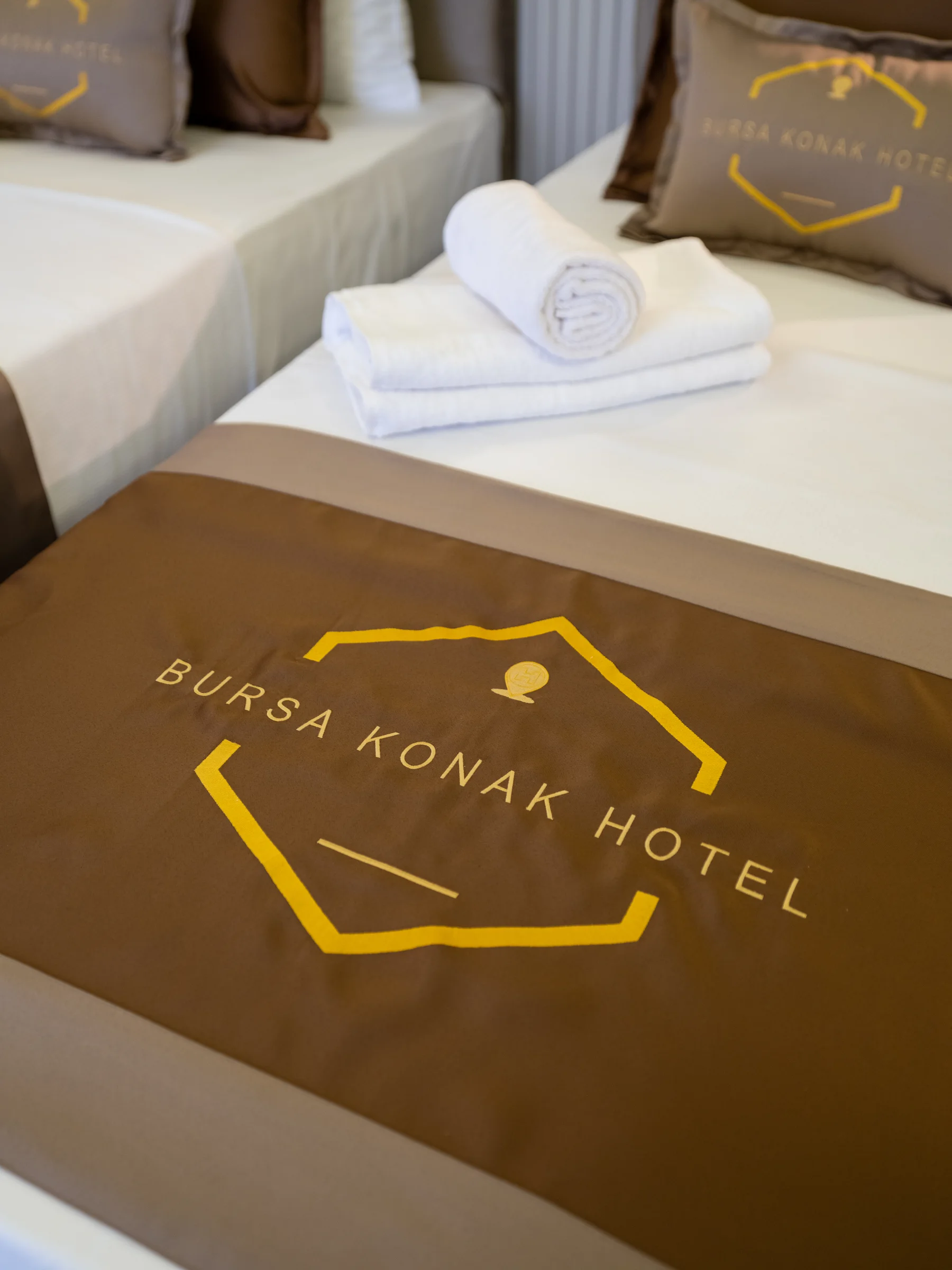 Yatak örtüsü üzerinde otel logosu ve havlu